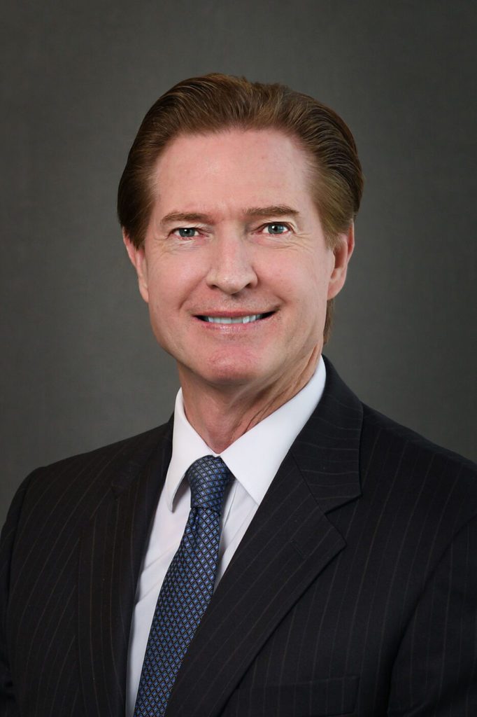 Headshot of a man in a suit and blue tie